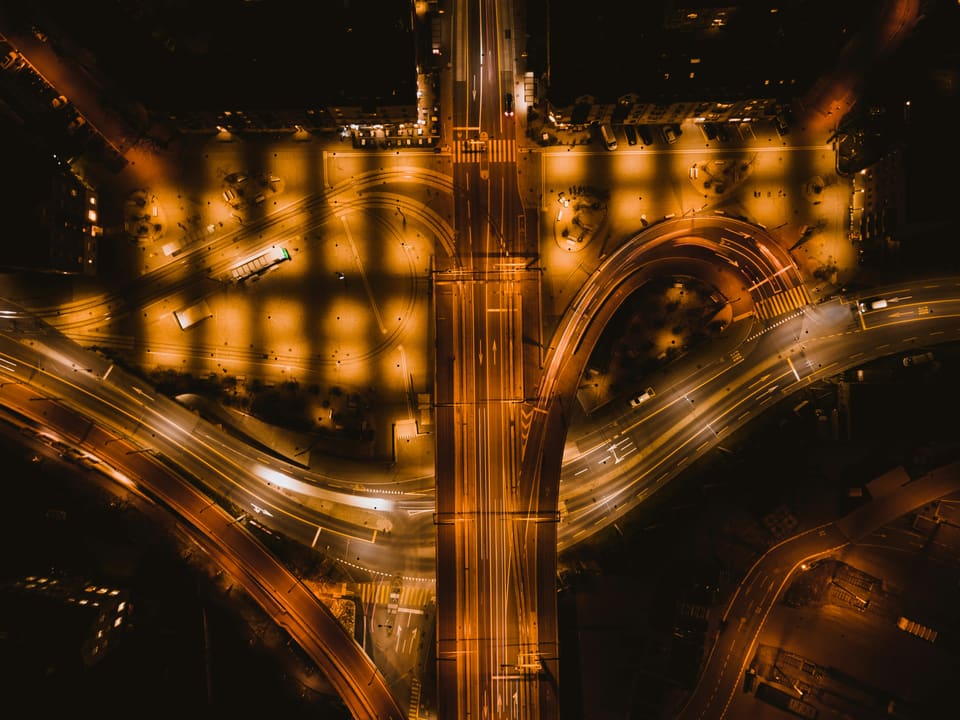Échangeur routier vu du ciel, de nuit, sillonné de traînées de phares