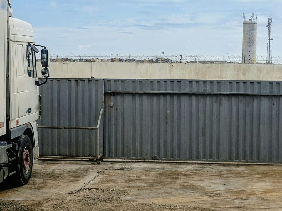Semi-remorque garé devant le portail coulissant d'un site clos
